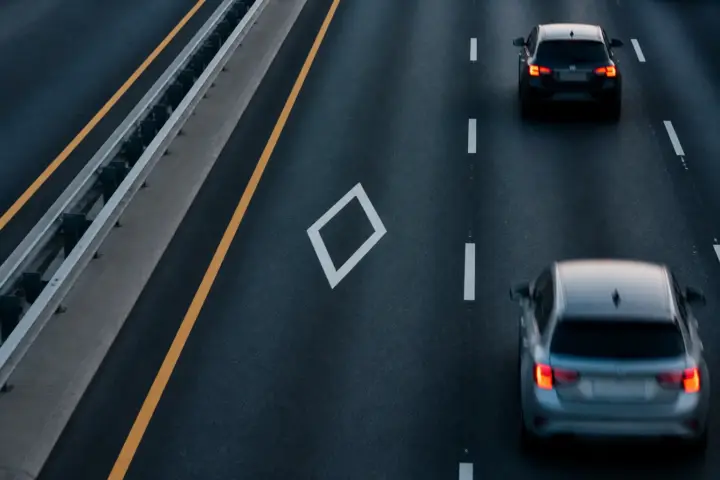 Route à plusieurs voies avec un losange blanc au sol sur la voie de gauche
