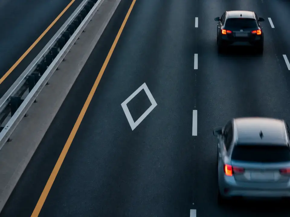 Route à plusieurs voies avec un losange blanc au sol sur la voie de gauche